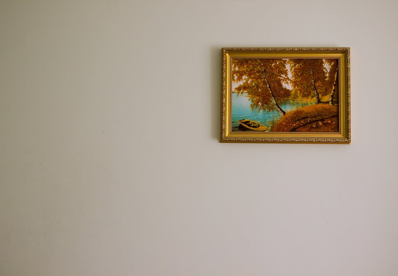 Minimalist interior with a framed landscape painting depicting serene autumn scenery.